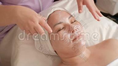 美容师用手捂住亚洲女人的脸，不接触皮肤。 美容中心VIP服务.. 女孩